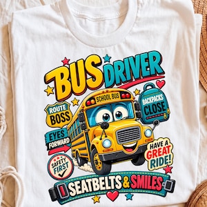 Puede incluir: Una camiseta blanca con un autobús escolar amarillo de dibujos animados con una cara sonriente. El gráfico incluye el texto BUS DRIVER, ROUTE BOSS, BACKPACKS CLOSE, EYES FORWARD, SAFETY FIRST, HAVE A GREAT RIDE y SEATBELTS & SMILES con estrellas.