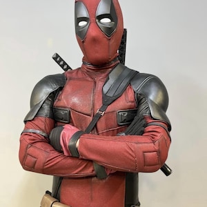 Puede incluir: Un disfraz de Deadpool rojo y negro, que incluye un body, una máscara, una armadura para los hombros y un cinturón de herramientas. El disfraz incluye una correa negra en el pecho, una hebilla con el logo de Deadpool y dos espadas en la espalda.