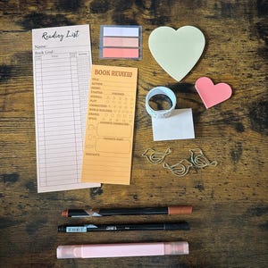 May include: A stationery set including a Reading List notepad, a Book Review notepad, three bird-shaped gold paper clips, a roll of patterned washi tape, heart-shaped sticky notes in yellow and pink, index tabs, and three pens in brown, black, and pink.