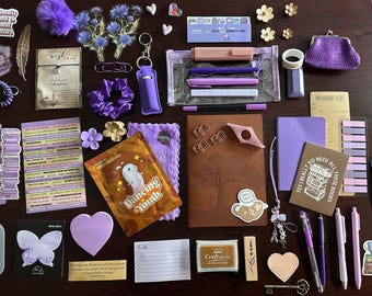 May include: A collection of stationery and accessories in shades of purple, including a brown notebook, pens, a purple coin purse, stickers, bookmarks, sticky notes, a clear pencil case, a small purple scrunchie, and various decorative paper clips.