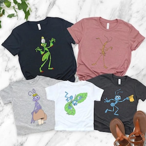 May include: A collection of five graphic t-shirts in various colors, each featuring a cartoon insect design. The shirts include a dark navy blue, dusty rose, gray, white, and charcoal gray. The designs include a green praying mantis, a stick insect, and various ants.