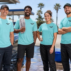 May include: Four individuals wearing matching light blue t-shirts with the text Your Logo Here printed on the chest, paired with dark trousers or shorts and baseball caps, standing in a car wash setting with cleaning supplies and a soapy vehicle.