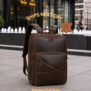May include: A dark brown leather backpack featuring a top handle, adjustable shoulder straps, and multiple zippered compartments. A leather-shaped tag on the right side reads Genuine 100% Leather. Text on the image includes SHIPS NEXT DAY and Premium Full-Grain Crazy Horse Leather.