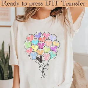 May include: Cream-coloured t-shirt with a colourful balloon design. The balloons are shaped like a mouse's head and are in various pastel colours. The text "Ready to press DTF Transfer" is at the top of the image.