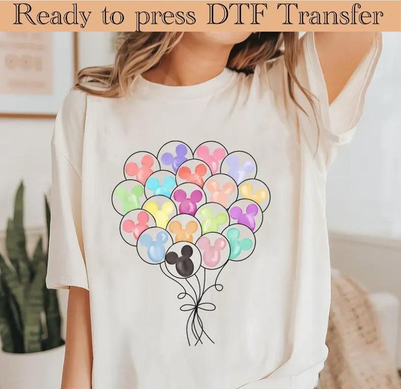 May include: Cream-coloured t-shirt with a colourful balloon design. The balloons are shaped like a mouse's head and are in various pastel colours. The text "Ready to press DTF Transfer" is at the top of the image.