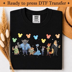Puede incluir: Una camiseta negra con un estampado gr&aacute;fico de siete personajes animales animados de pie en fila, cada uno sosteniendo un globo de colores con forma de cabeza de rat&oacute;n. Los personajes incluyen un perezoso, un b&uacute;falo, un castor, una serpiente, un conejo, un zorro y un caballo.