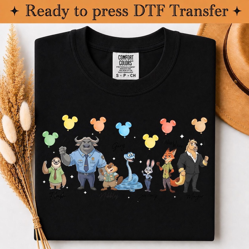 Puede incluir: Una camiseta negra con un estampado gr&aacute;fico de siete personajes animales animados de pie en fila, cada uno sosteniendo un globo de colores con forma de cabeza de rat&oacute;n. Los personajes incluyen un perezoso, un b&uacute;falo, un castor, una serpiente, un conejo, un zorro y un caballo.