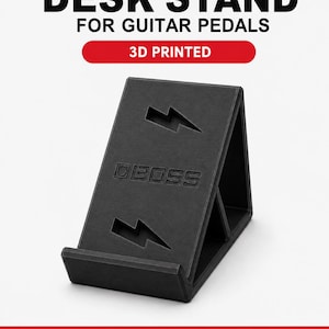 May include: A black 3D printed desk stand for guitar pedals with a triangular profile. The front face features the embossed text BOSS, two lightning bolt cutouts, and a bottom ledge to support a pedal. Text reads DESK STAND FOR GUITAR PEDALS.