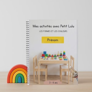 Peut inclure: Un livre d'activités pour enfants intitulé "Mes activités avec Petit Lulu" avec le sous-titre "Les Formes et les Couleurs". Un arc-en-ciel en bois et une table avec des formes en bois sont également visibles. Le livre est pour les 3-6 ans.
