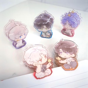 May include: Five acrylic anime-style character charms. Each charm features a different character with unique hair colors, outfits, and poses. The charms have a clear, glossy finish and are set on colorful bases.