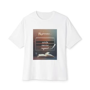 May include: White t-shirt with a graphic that reads "write, revise, repeat" in a handwritten style. The design includes an open book and a pen, with the phrase "the process..." above. The shirt is a casual, everyday wear item.