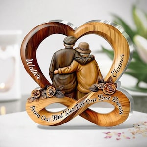 May include: A wooden and acrylic heart-shaped keepsake featuring an elderly couple embracing. The design includes the names "Walter" and "Eleanor" and the phrase "From Our First Kiss Till Our Last Breath". Decorative roses are also included.