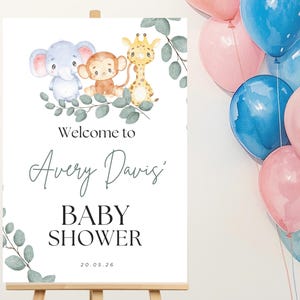 May include: A white rectangular sign featuring watercolor illustrations of a blue elephant, a brown monkey, and a yellow giraffe surrounded by green eucalyptus leaves. The text reads Welcome to Avery Davis' BABY SHOWER and 20.05.26.
