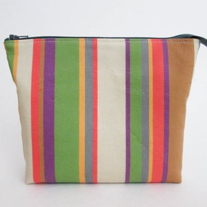 May include: A striped zippered pouch with a beige background and colorful stripes in shades of green, purple, orange, and red.