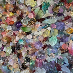 May include: A large collection of assorted translucent and opaque acrylic beads in various shapes including flowers, leaves, butterflies, and geometric forms. The beads feature a wide spectrum of pastel and vibrant colors with iridescent finishes.