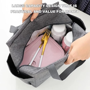 May include: Gray insulated lunch bag with a zipper closure and handles. The bag contains a pink lunch container, two white bottles, and gold-colored forks. Text on the bag reads: LARGE CAPACITY DESIGN THAT IS PRACTICAL AND VALUE FOR MONEY.