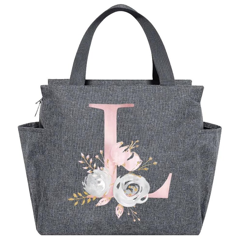 May include: Gray insulated lunch bag with a pink letter "L" and floral design. The bag has a top handle, side pockets, and a zipper closure. The floral design includes white and pink roses with gold accents.