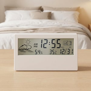 May include: A rectangular white digital clock with a clear LCD screen displaying the time 12:55, the date 12/31, the day WED, a temperature of 35°C, and a humidity level of 54%. The screen also features a weather icon showing a sun and clouds.