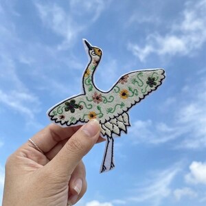 Geborduurde kraanvogelpatch met gebloemde vleugels – opstrijkjack rugzakdecor