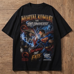 May include: Black t-shirt featuring a graphic design with the text "Mortal Kombat vs DC Universe." The design depicts two characters facing each other with lightning and a blue and red color scheme. The shirt is made of a soft material.