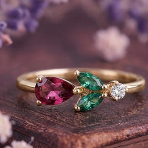 Könnte beinhalten: Ein Set aus drei Keramikbechern mit gesprenkelter, matter Oberfläche. Die Becher sind in Creme-, Hellgrau- und Dunkelgrautönen gehalten. Jeder Becher hat ein schlichtes, minimalistisches Design und einen abgerundeten Henkel.