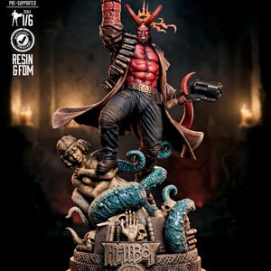 Può includere: Statua in resina dettagliata di Hellboy, un demone dalla pelle rossa con le corna, che tiene una pistola e alza il pugno destro. La statua è su una base con teschi e tentacoli. La figura indossa un cappotto marrone e pantaloni scuri.