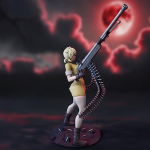 May include: A figurine of a blonde character wearing a tan shirt and shorts, white thigh-high stockings, and dark boots. The character holds a large grey machine gun with a long, curved ammunition belt hanging down toward a circular base with scattered bullets.