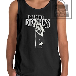 May include: Black tank top featuring the band name "The Pretty Reckless" in white block letters above a black and white graphic of a woman holding a microphone stand. The tank top is sleeveless and has a rounded neckline.