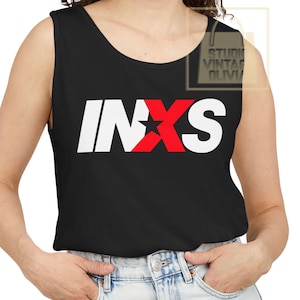 May include: Black tank top featuring the band name INXS in white block letters with a red star and X design. The tank top is sleeveless and made of a soft material.