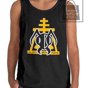 May include: Black tank top featuring a yellow and black graphic design. The design includes an ant-like figure within a yellow triangle, with the text "ALIEN ANT FARM" in yellow. The tank top is sleeveless.