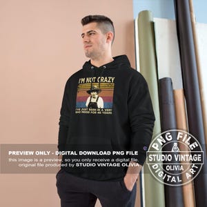 May include: Black hoodie with a graphic that reads "I'M NOT CRAZY" above an image of a person in a hat and overalls. The text below says "I'VE JUST BEEN IN A VERY BAD MOOD FOR 40 YEARS".