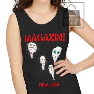 Peut inclure: Un débardeur noir sans manches avec le texte rouge MAGAZINE en haut et REAL LIFE en bas. Le motif central présente quatre illustrations de visages stylisées et abstraites en blanc, noir et couleurs sourdes sur un fond sombre.