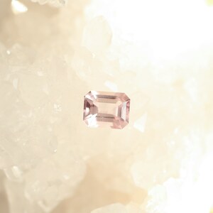 May include: A pale pink gemstone with a rectangular emerald cut.