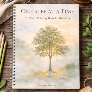 May include: A spiral-bound coloring book titled "ONE STEP AT A TIME" with a watercolor illustration of a tree. The book is for recovery and has the text "A 12-Step Coloring Book for Recovery". Colored pencils, a cup of coffee, and twine are also visible.