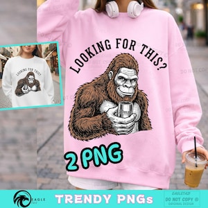 Puede incluir: Sudadera rosa con el texto "LOOKING FOR THIS?" y un gráfico de un gorila sosteniendo un vaso de 10 mm. La imagen también incluye el texto "2 PNG" y "TRENDY PNGS".