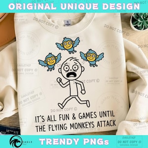 May include: Cream-colored sweatshirt with a graphic of a stick figure running from three cartoon monkeys with blue wings. The text "IT'S ALL FUN & GAMES UNTIL THE FLYING MONKEYS ATTACK" is printed below the graphic. The words "ORIGINAL UNIQUE DESIGN" are at the top.