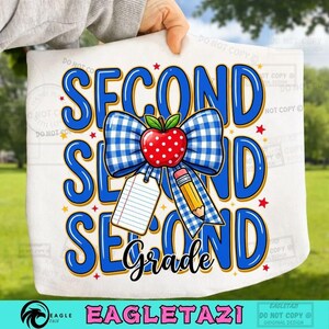 Può includere: Una superficie in tessuto bianco con il testo blu SECOND GRADE, un fiocco a quadretti blu e bianco, una mela rossa con pois bianchi, una matita gialla e un'etichetta di carta a righe bianca, il tutto accentuato da piccole stelle rosse.