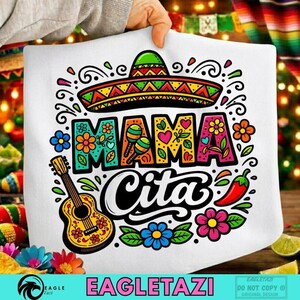 Peut inclure: Coussin blanc avec un motif coloré représentant un sombrero, les mots "MAMA CITA", des fleurs, une guitare, des maracas et un piment. Le design utilise des couleurs vives avec des contours noirs.