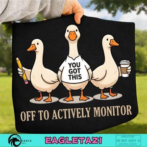 May include: Black tote bag with a cartoon design of three geese. One goose holds a pencil, another wears a shirt with "YOU GOT THIS," and the third holds a coffee cup. The text "OFF TO ACTIVELY MONITOR" is below the geese.