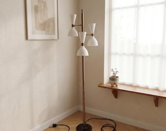 May include: A floor lamp featuring a tall, slender metallic brown pole with a circular black base. It has four white, cone-shaped shades arranged at different heights and angles, each connected to the central pole by short, horizontal metallic arms.