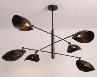 May include: A dark bronze metal chandelier featuring a central vertical rod with six adjustable arms extending outward. Each arm terminates in a bowl-shaped shade with a distressed finish, housing a small light bulb that emits a warm glow.