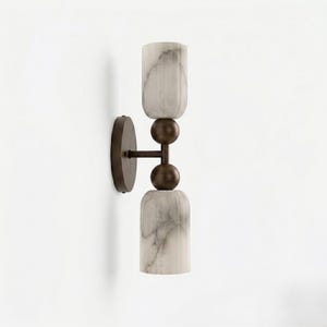 May include: A wall sconce featuring two marble-like, cylindrical shades with a dark bronze-colored metal frame. The shades have a light gray and white veined pattern. The sconce is mounted on a round, dark bronze base.