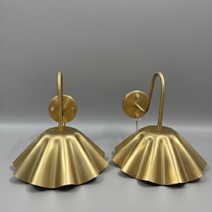 8-inch tall scalloped brass gooseneck wall sconces in a brushed satin finish, featuring 10-inch fluted shades and 5-inch round canopies projecting 15 inches from the wall.