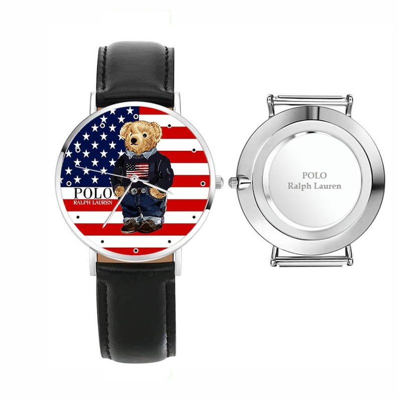 May include: A wristwatch with a black leather band and a round face. The watch face features a bear wearing a jacket and jeans, set against a backdrop of the American flag. The watch also has the text "POLO Ralph Lauren".