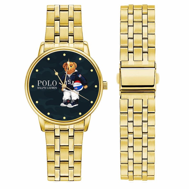 May include: Gold-tone wristwatch with a dark navy face featuring a bear graphic wearing a jacket and holding a basketball. The watch has a matching gold-tone band. The watch face displays the text "POLO RALPH LAUREN".