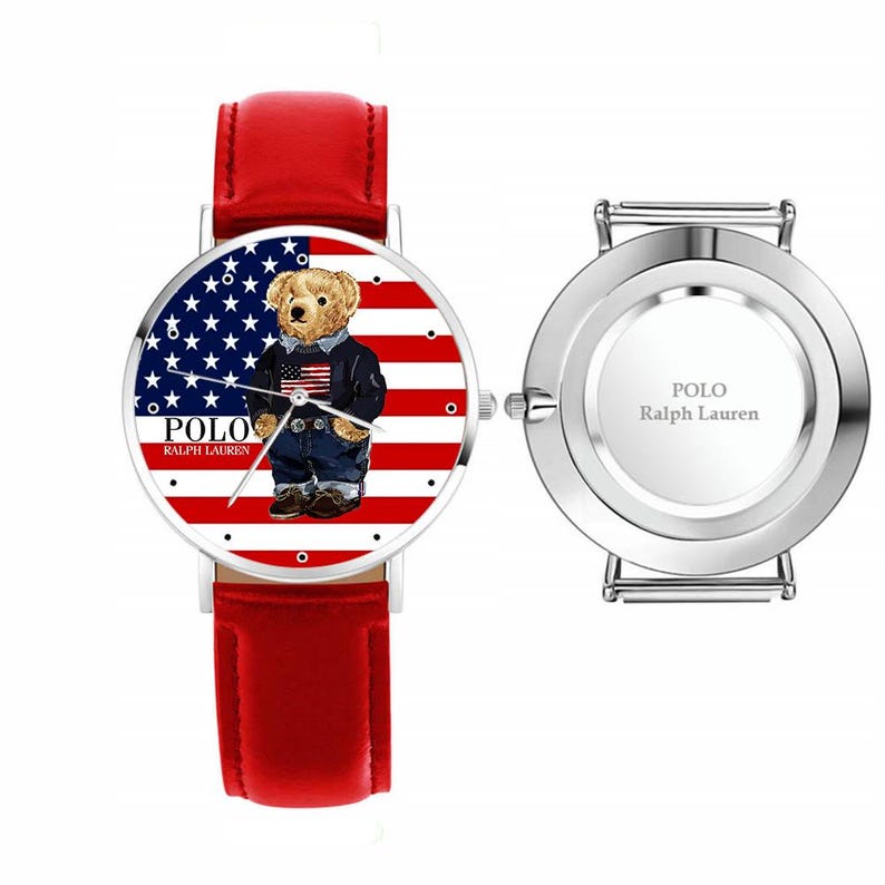 May include: A wristwatch with a red leather band and a silver-colored case. The watch face features a bear wearing a jacket and jeans, set against a backdrop of the American flag. The text "POLO Ralph Lauren" is printed on the watch face.