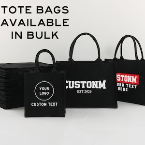 Peut inclure: Une collection de sacs fourre-tout noirs avec des anses noires, présentant divers logos et textes personnalisés en blanc et rouge. Une pile de sacs pliés se trouve à gauche. Le texte TOTE BAGS AVAILABLE IN BULK est imprimé en haut.
