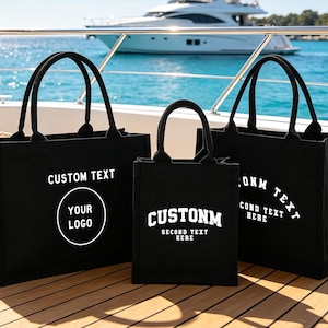 Könnte beinhalten: Drei schwarze Tragetaschen aus Segeltuch mit stabilen Griffen. Die linke Tasche zeigt den weißen Text CUSTOM TEXT und YOUR LOGO. Die mittlere Tasche zeigt CUSTOMN und SECOND TEXT HERE. Die rechte Tasche zeigt CUSTOM TEXT und SECOND TEXT HERE.