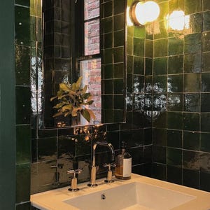 Könnte beinhalten: Eine weiße Keramik-Tasse mit schwarzem Henkel und dem Text "But First, Coffee" in fetter, schwarzer Schrift. Die Tasse steht vor einem neutralen Hintergrund, der ihr schlichtes Design hervorhebt.