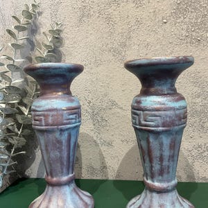 K&ouml;nnte beinhalten: Zwei dekorative Kerzenhalter im antiken Stil mit Used-Look. Die Halterungen sind in Blau-, Braun- und Lilat&ouml;nen gehalten. Sie weisen ein griechisches Schl&uuml;sselmuster und einen geriffelten Sockel auf. H&ouml;he ca. 15 cm.